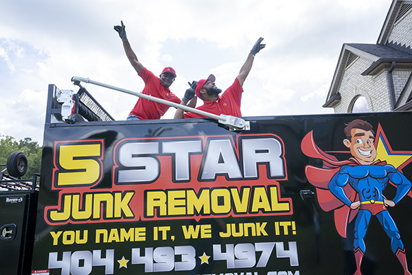 Junk removal workers striking a pose while inside the 5 Star Junk Removal truck